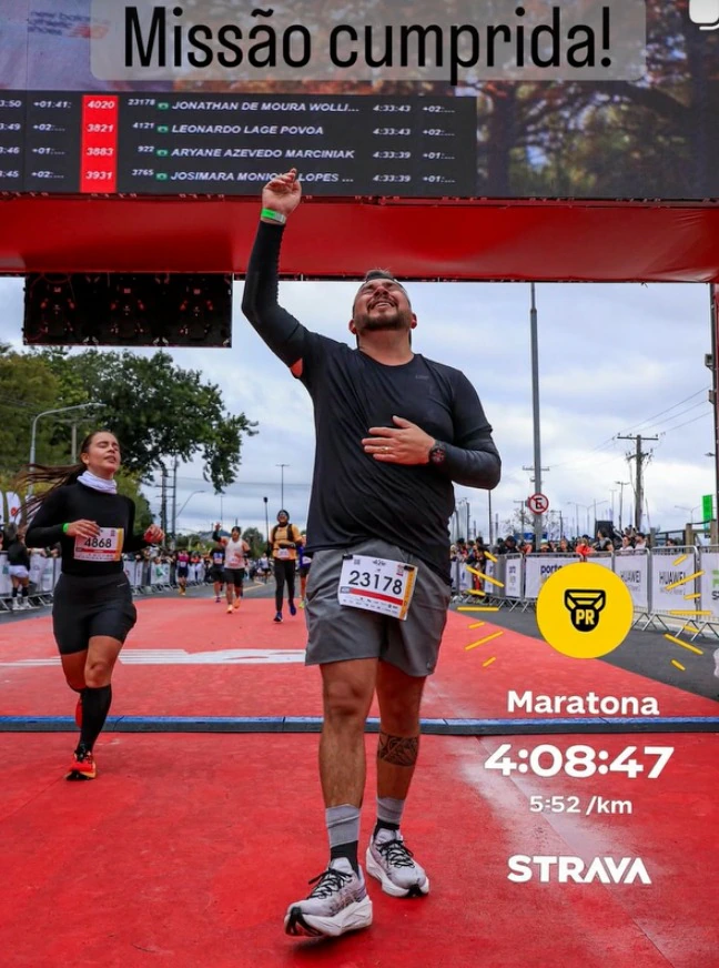 Corredor na chegada de uma maratona, com registro do tempo.